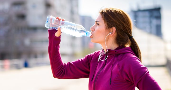 A woman drinking water before a run.
