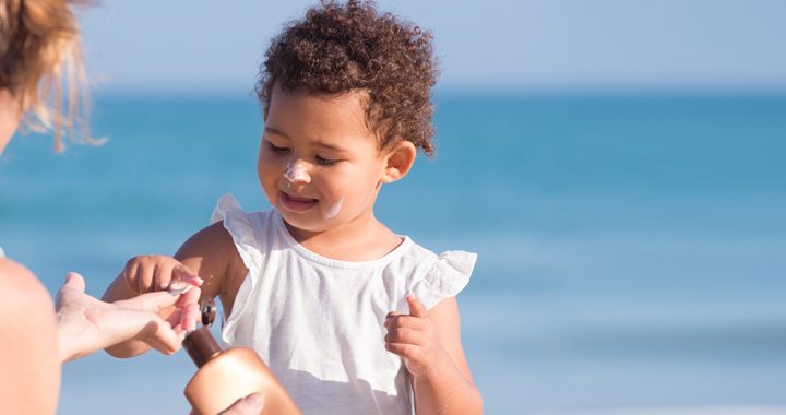 mother helps daughter apply sunscreen_ sun safety tips
