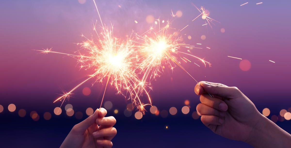 Two people holding sparkler fireworks.