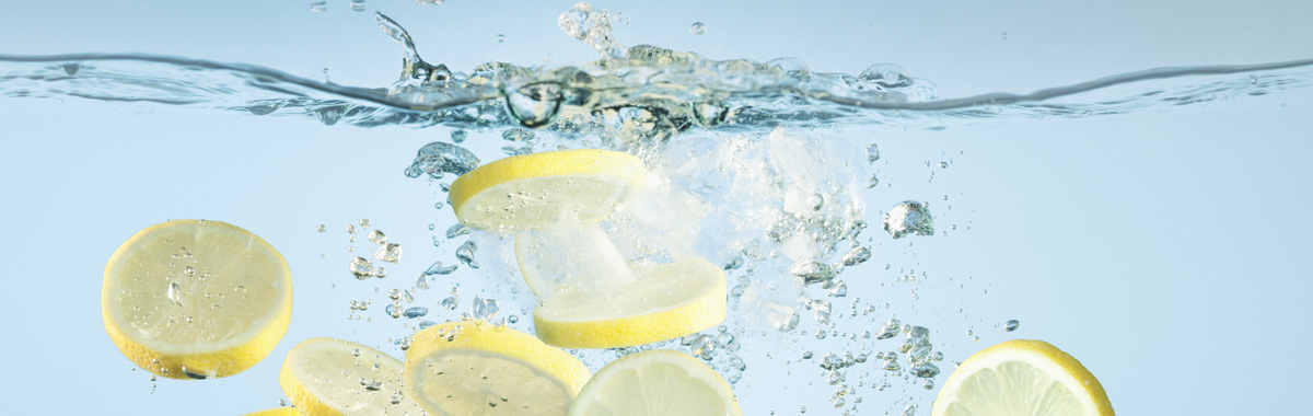 slices of lemon splash into fresh water _ benefits of drinking lemon water