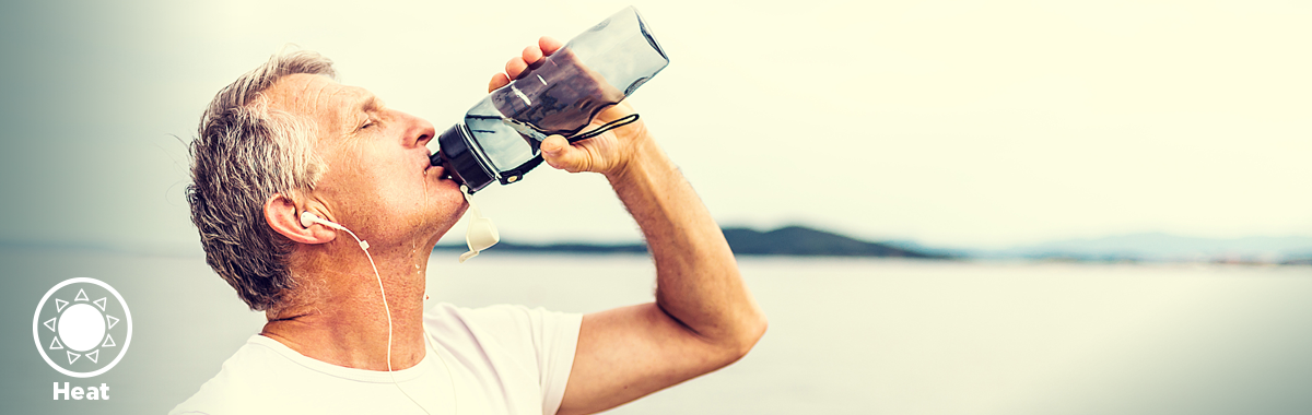 man drinks from water bottle on a beach _ how to protect your heart from the heat