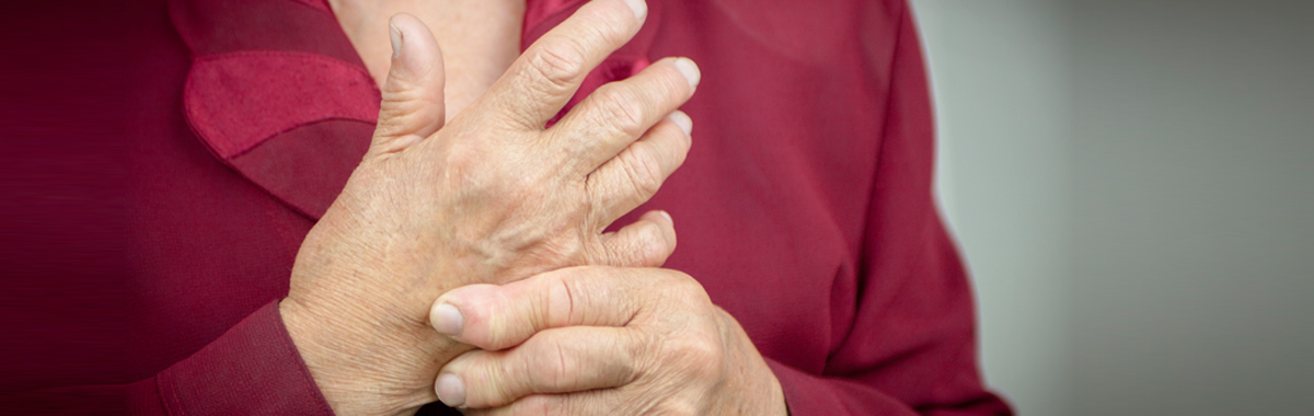 woman massages her own hand _ rheumatoid arthritis