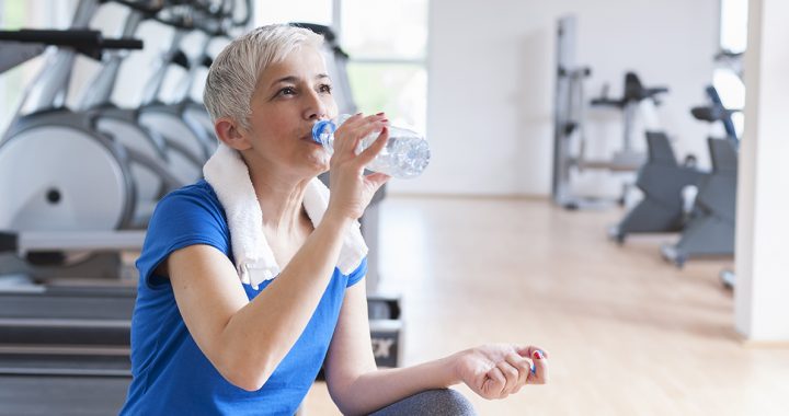 A woman drinking water during her workout.