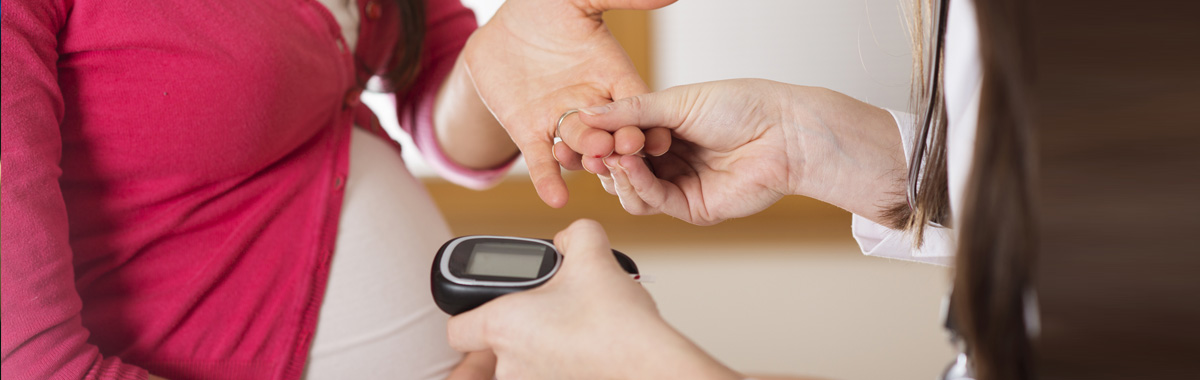close-up of healthcare worker using blood glucose meter to test pregnant woman's blood sugar - gestational diabetes