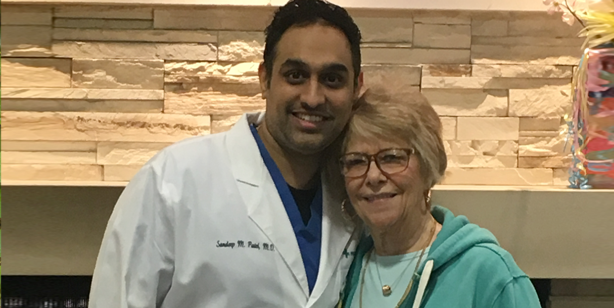 Nancy Paul stands smiling next to Dr. Sandeep Patel who performed her TMVR surgery