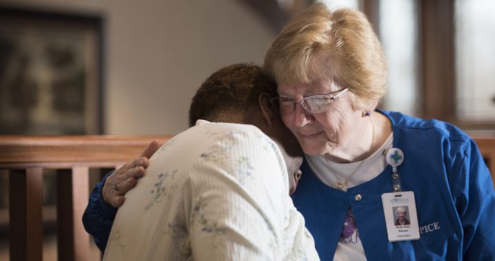 A hospice volunteer holds a patient in a hug