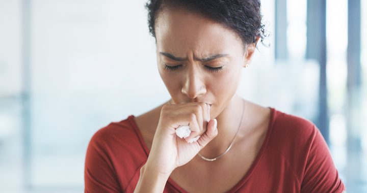 Woman experiencing a cough, one of the COVID-19 symptoms.