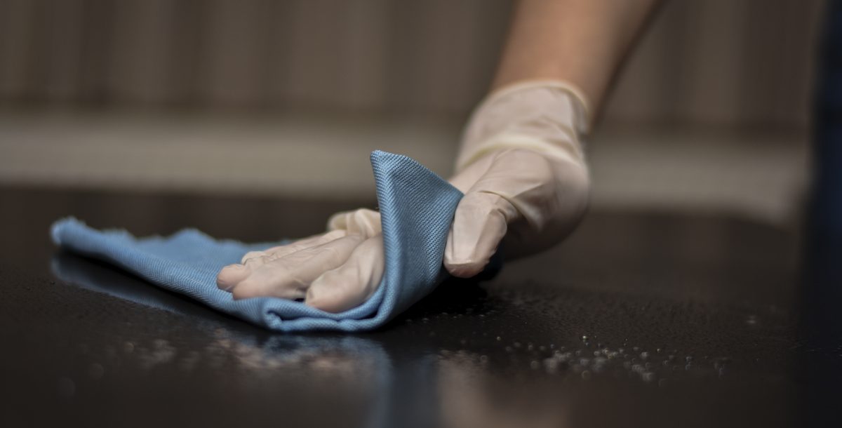 Person cleaning and disinfecting a surface in their home