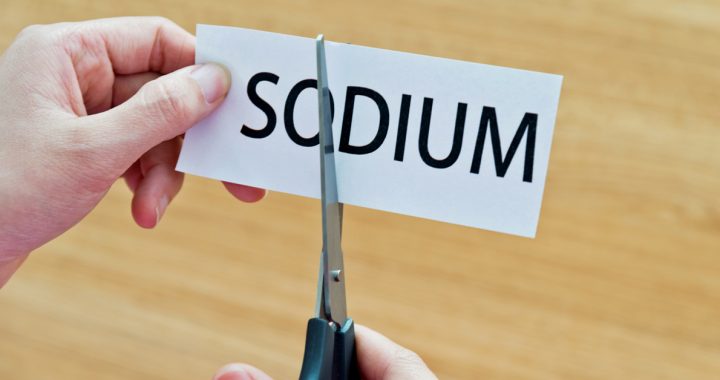 Scissors cutting the word "sodium" on a piece of paper.