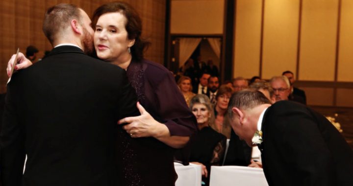 Sharon and Josh embracing at his wedding ceremony.