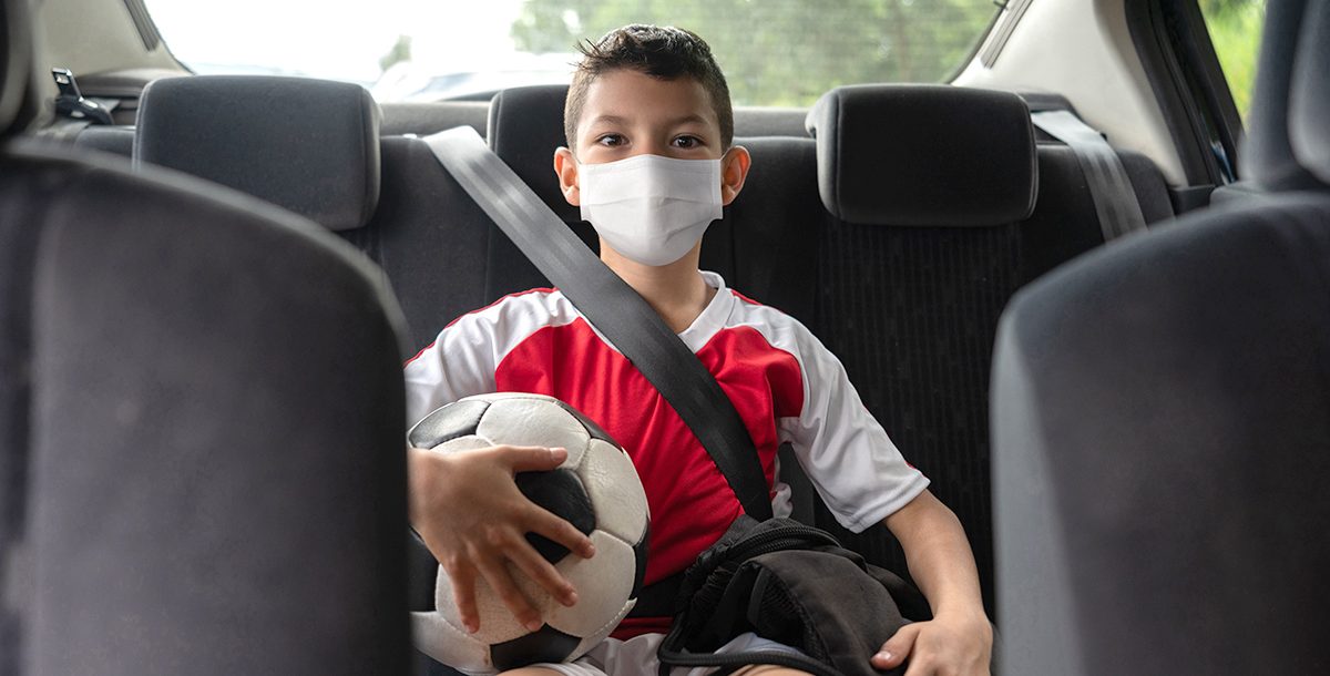 A boy going to his soccer game wearing a face mask during COVID-19.
