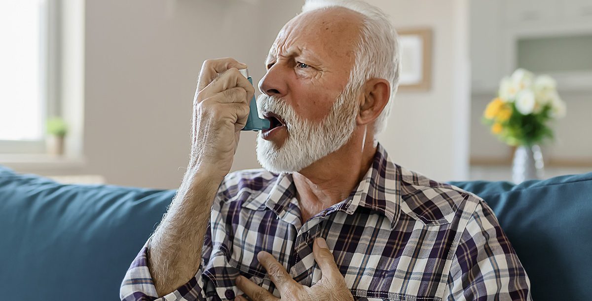 A man suffering from asthma using an inhaler.