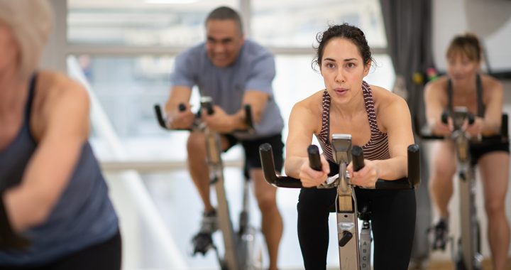 A woman participating in a cycle class at the gym during COVID-19.