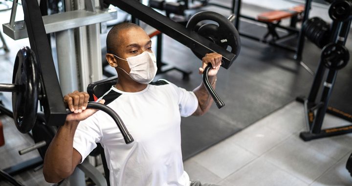 A man exercising at the gym while wearing a face mask during COVID-19.