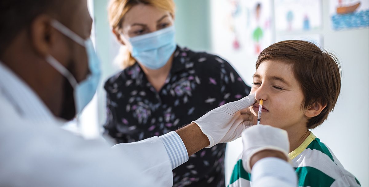 A kid getting the nasal spray flu vaccine from his primary care provider.