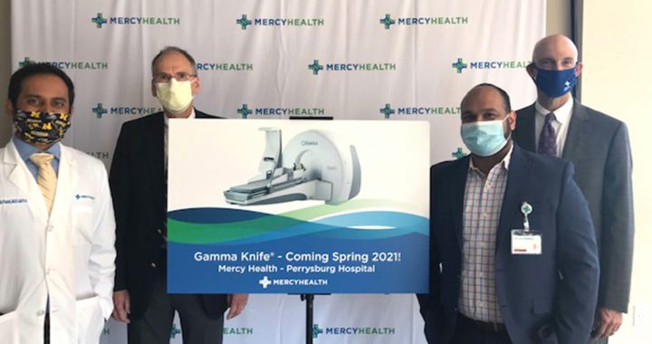 Mercy Health Perrysburg Hospital leadership team members stand surrounding a poster depicting a gamma knife machine