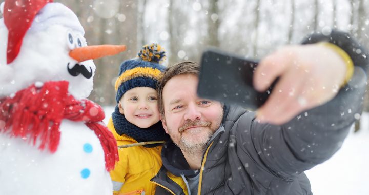 A father and son participating in a virtual snowman decorating contest.