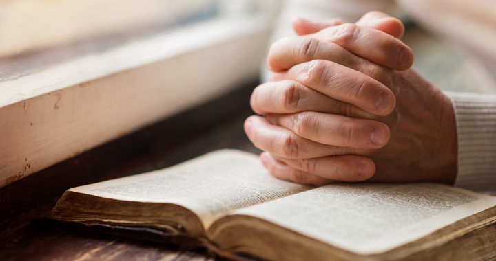 A person praying using a bible.