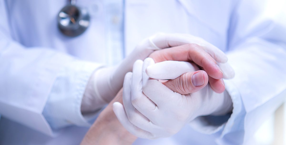 A health care provider holding a patient's hand.