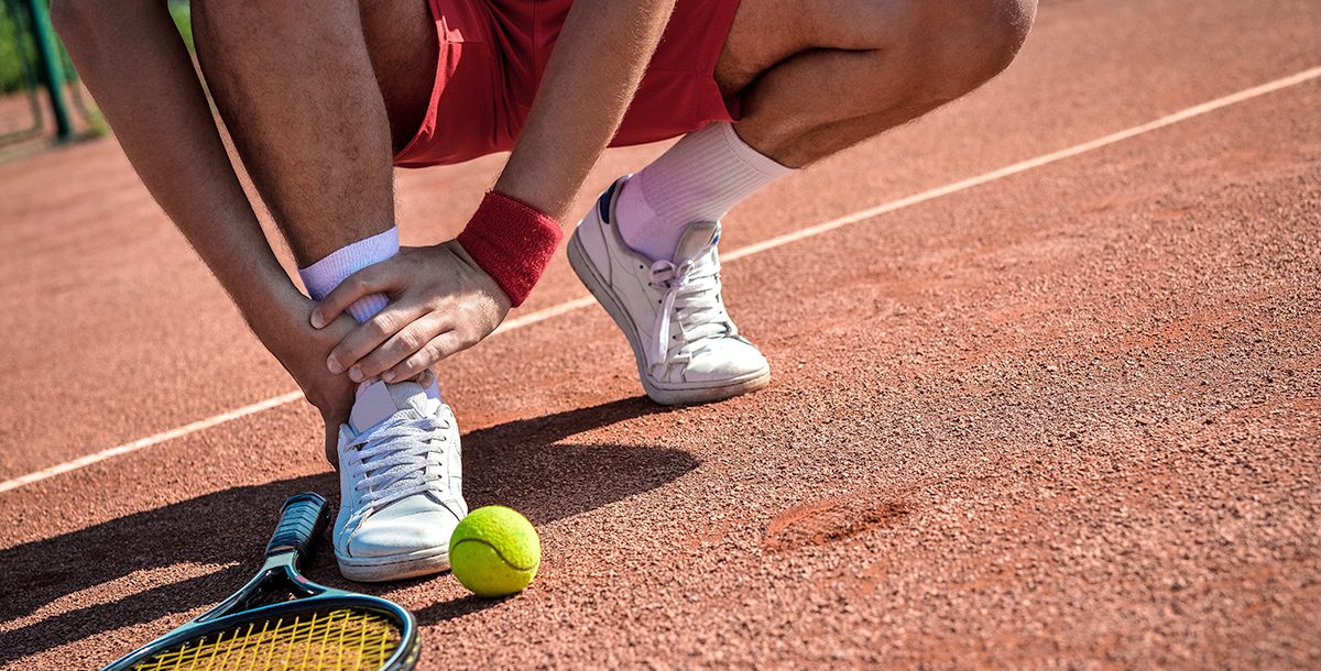 A person experiencing an ankle injury while playing tennis.