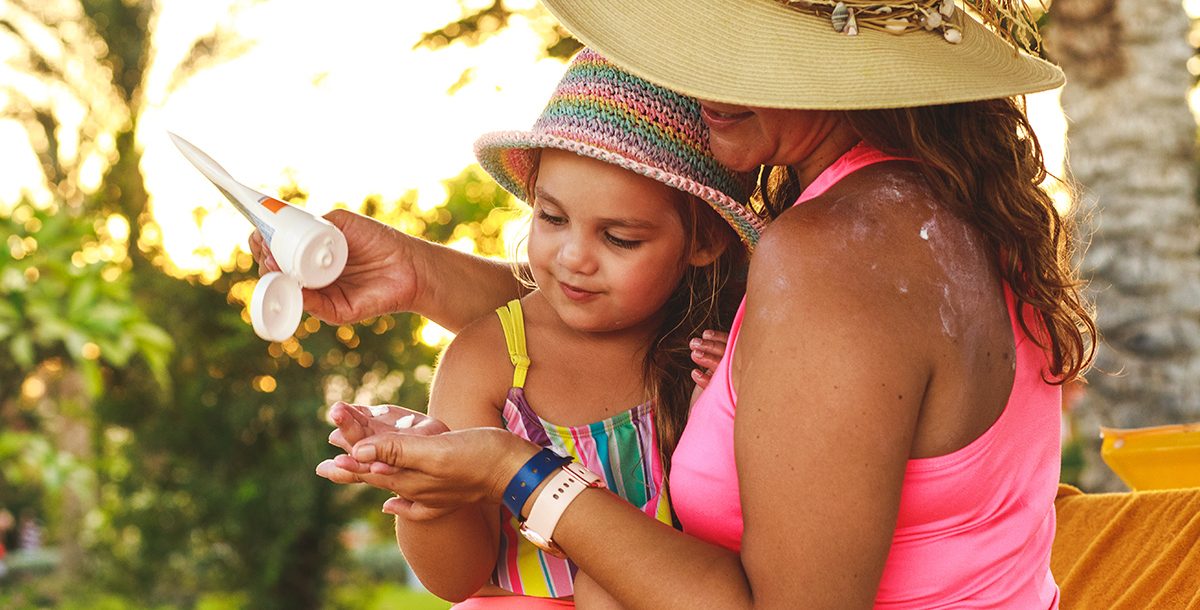 A mother putting sunscreen on her daughter.
