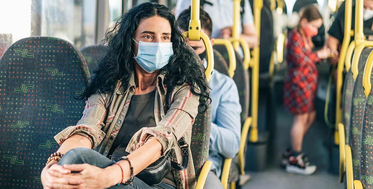 A woman wearing a face mask on public transportation.