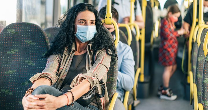 A woman wearing a face mask on public transportation.