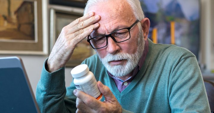 A man looking at a medication bottle.