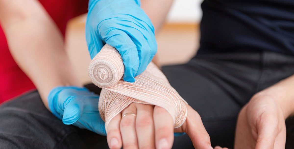 An emergency care professional wraps a patient's hand as part of proper snake bite treatment.