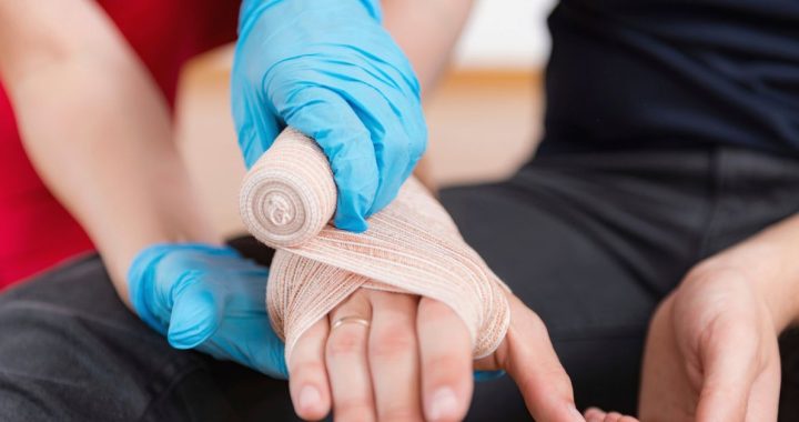 An emergency care professional wraps a patient's hand as part of proper snake bite treatment.